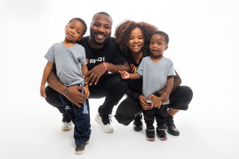A joyful family with two children smiling against a white backdrop.